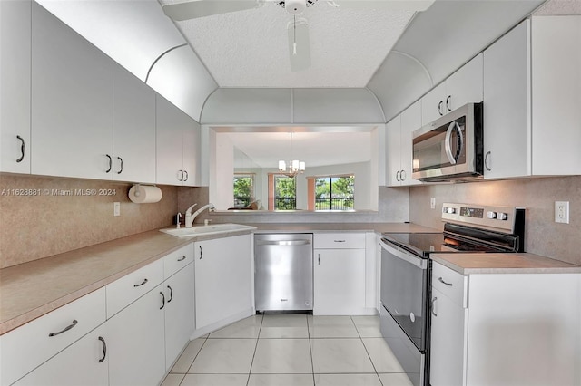 kitchen with decorative light fixtures, tasteful backsplash, sink, white cabinets, and stainless steel appliances