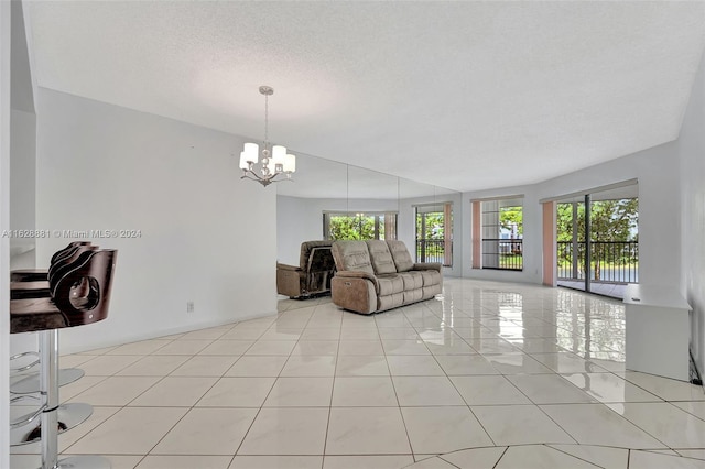 unfurnished living room with a chandelier, light tile patterned floors, and a textured ceiling