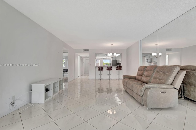 living room with light tile patterned floors, a notable chandelier, and a textured ceiling