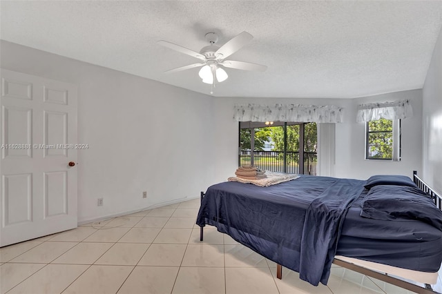 tiled bedroom featuring ceiling fan, access to outside, and a textured ceiling