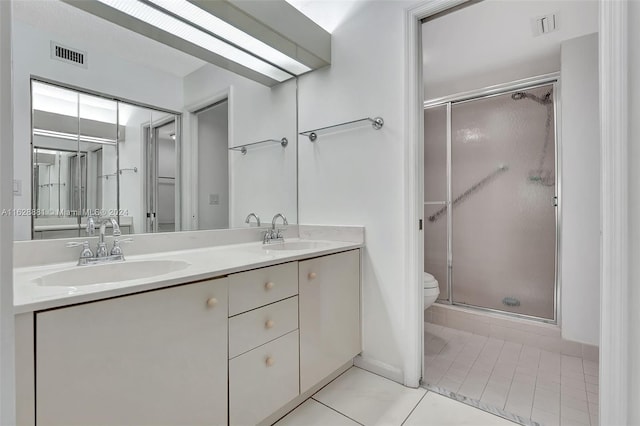 bathroom with tile patterned flooring, vanity, a shower with shower door, and toilet