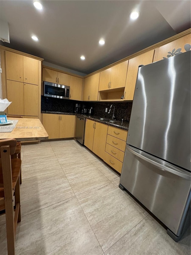 kitchen featuring light tile patterned flooring, dark stone countertops, tasteful backsplash, appliances with stainless steel finishes, and light brown cabinetry