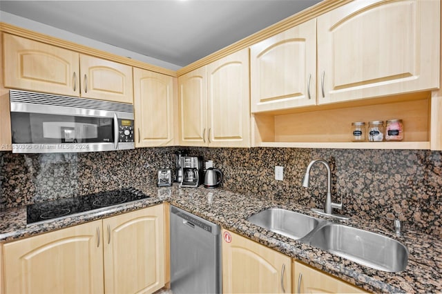 kitchen featuring dark stone counters, backsplash, appliances with stainless steel finishes, and sink