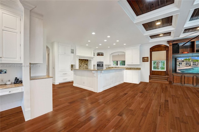 kitchen featuring coffered ceiling, ornamental molding, a kitchen breakfast bar, and white cabinets