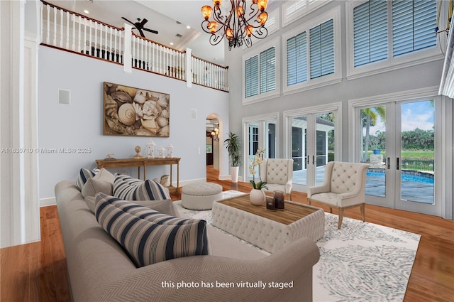 living room featuring hardwood / wood-style floors, a towering ceiling, a notable chandelier, and french doors