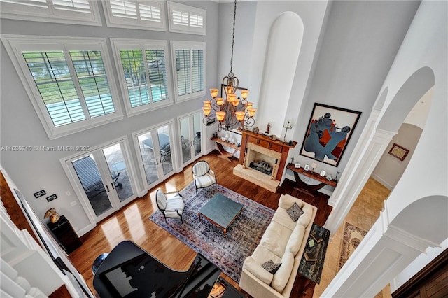 living room with a notable chandelier, hardwood / wood-style flooring, and a high ceiling