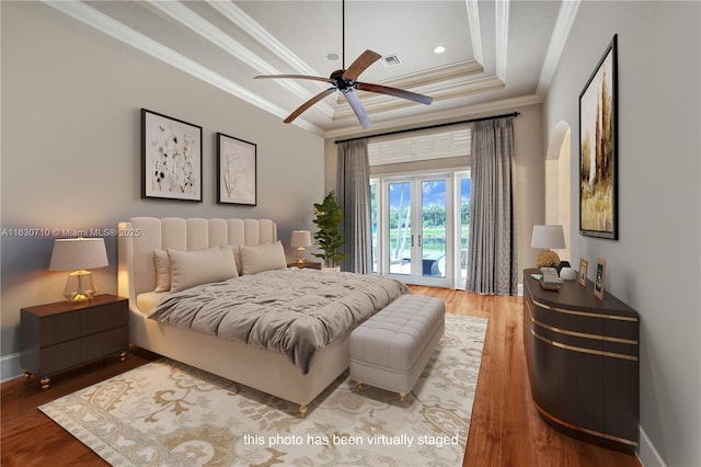 bedroom featuring hardwood / wood-style floors, ornamental molding, access to outside, ceiling fan, and a raised ceiling