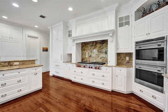 kitchen with backsplash, light stone countertops, white cabinets, and appliances with stainless steel finishes