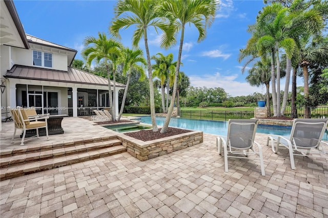 view of swimming pool featuring an in ground hot tub, a sunroom, and a patio