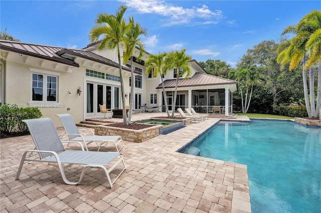 view of pool with an in ground hot tub, a sunroom, and a patio