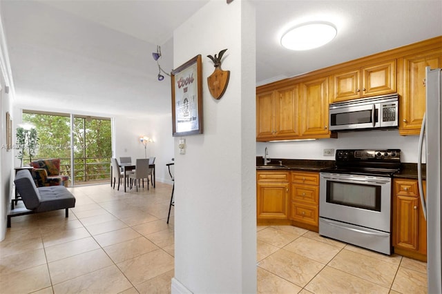 kitchen with floor to ceiling windows, appliances with stainless steel finishes, light tile patterned floors, and sink