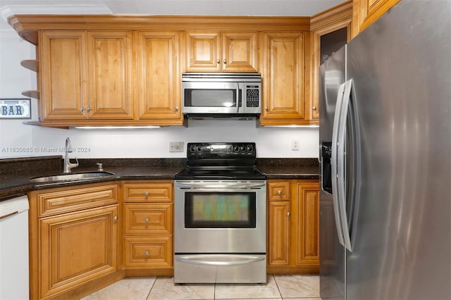 kitchen with stainless steel appliances, sink, dark stone counters, and light tile patterned flooring