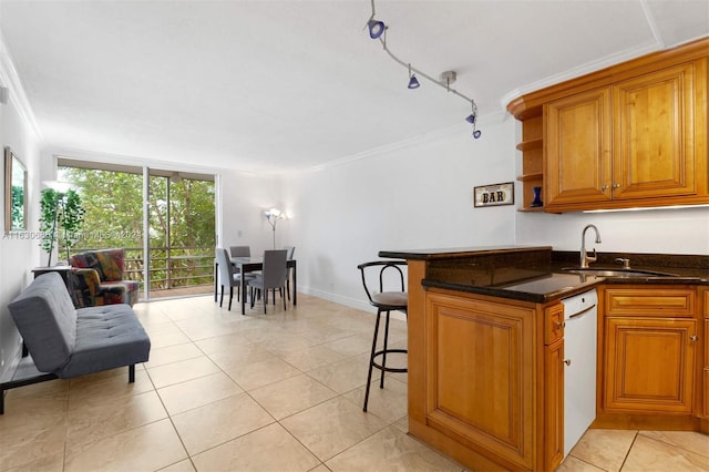 kitchen with a kitchen breakfast bar, crown molding, sink, rail lighting, and light tile patterned flooring