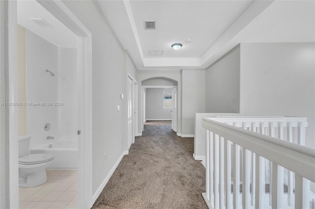 hall featuring light carpet and a tray ceiling