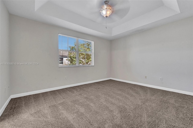 carpeted empty room with ceiling fan and a raised ceiling