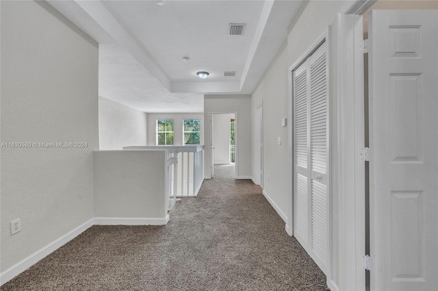 corridor featuring carpet floors and a raised ceiling