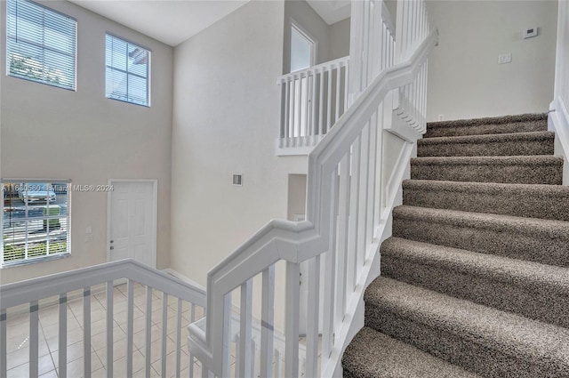 staircase with tile patterned floors and a towering ceiling