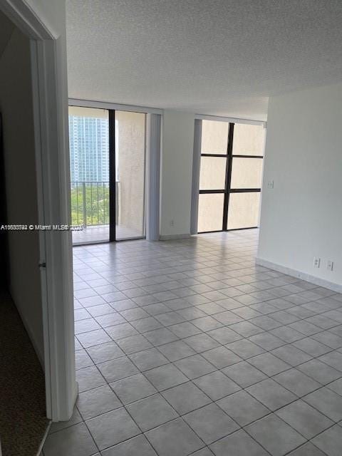 spare room featuring light tile patterned flooring, expansive windows, and a textured ceiling