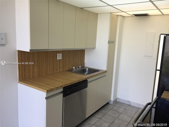 kitchen with sink, dishwasher, cream cabinetry, refrigerator, and light tile patterned floors