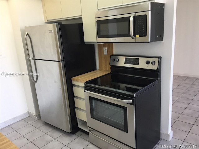 kitchen with white cabinetry, stainless steel appliances, and light tile patterned floors