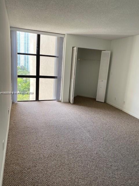 unfurnished bedroom with a textured ceiling and light colored carpet