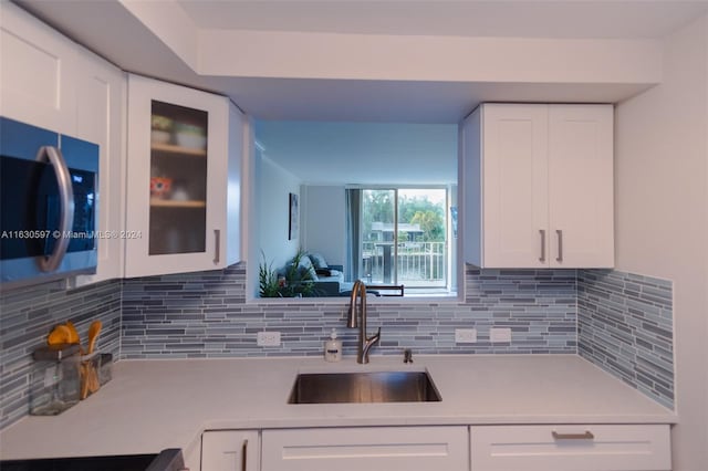 kitchen featuring decorative backsplash, white cabinetry, and sink