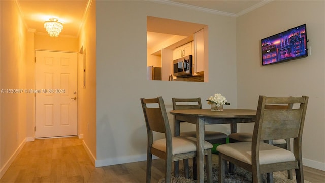 dining area featuring light hardwood / wood-style flooring, ornamental molding, and a notable chandelier