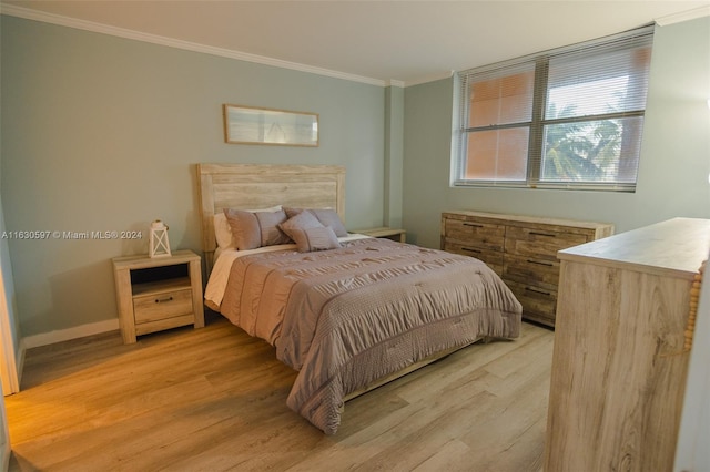 bedroom with ornamental molding and light hardwood / wood-style floors