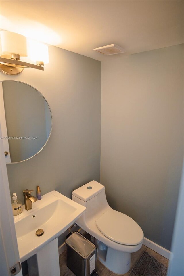 bathroom with toilet, sink, and hardwood / wood-style floors