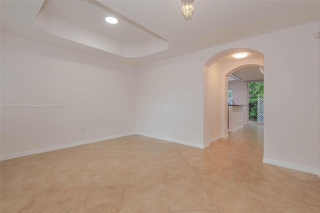 tiled spare room with a raised ceiling