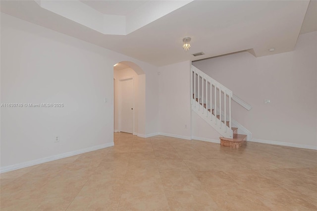 spare room featuring light tile patterned floors, baseboards, visible vents, arched walkways, and stairs