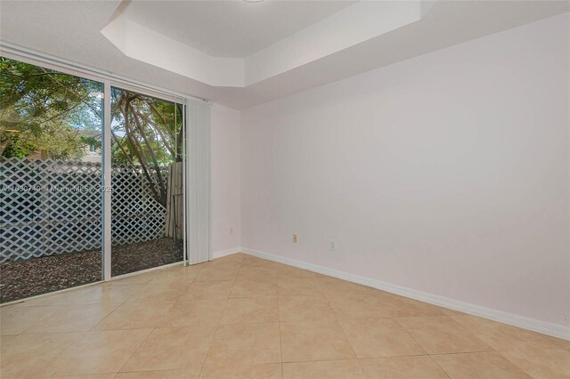 unfurnished room featuring a raised ceiling and light tile patterned floors