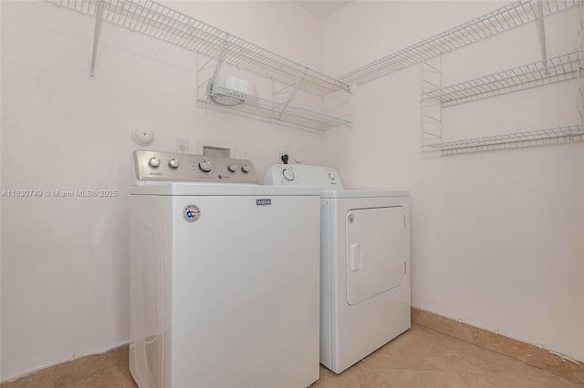 laundry area with washer and dryer, laundry area, baseboards, and light tile patterned floors