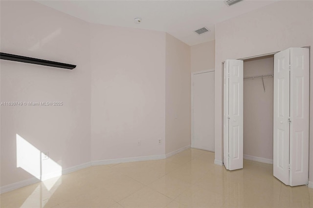 unfurnished bedroom with light tile patterned floors, baseboards, visible vents, and a closet