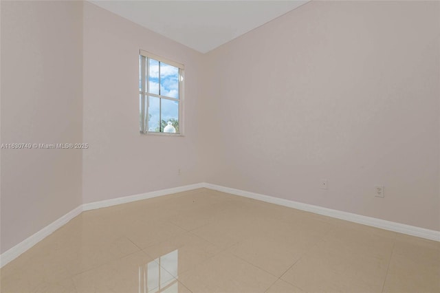 spare room featuring light tile patterned flooring and baseboards