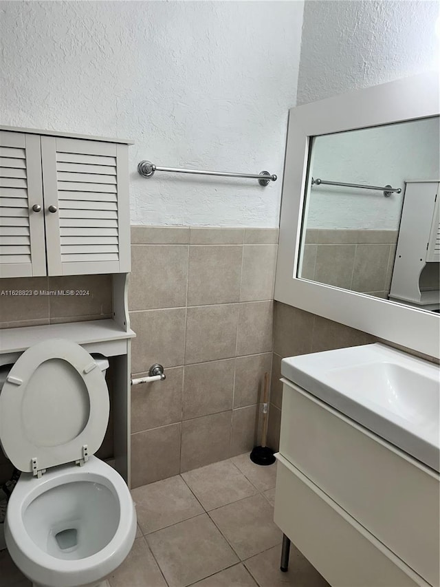 bathroom with vanity, tile patterned floors, tile walls, and toilet