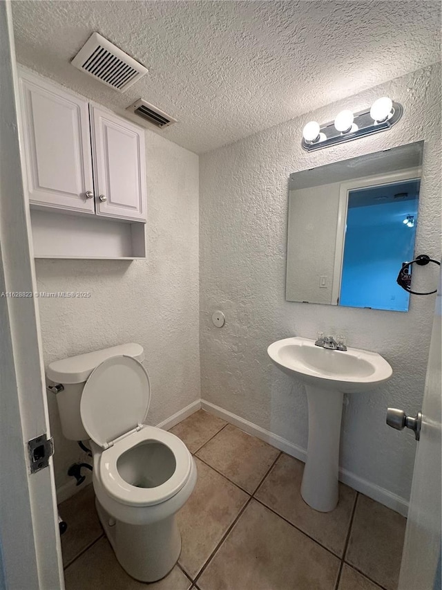 bathroom featuring toilet, sink, tile patterned flooring, and a textured ceiling