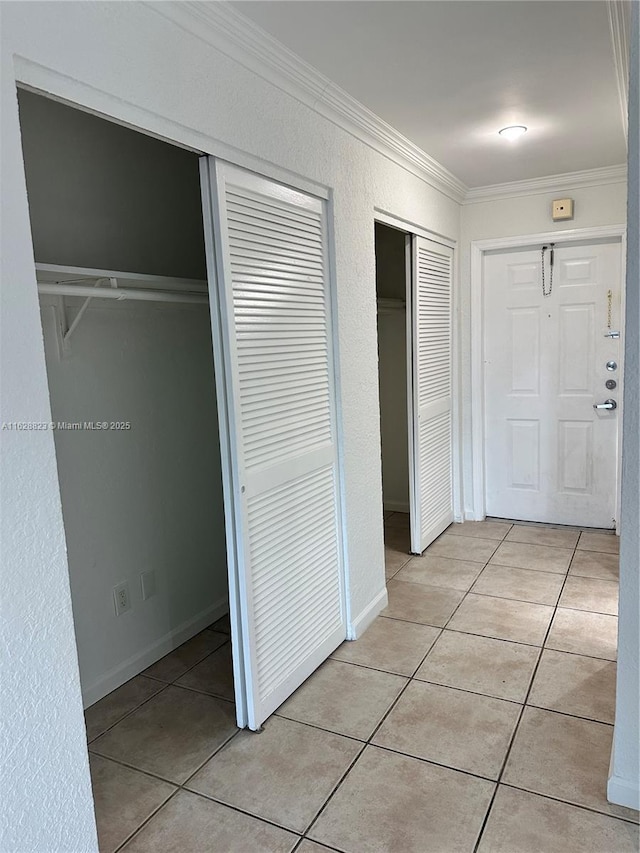 hallway featuring ornamental molding and light tile patterned floors