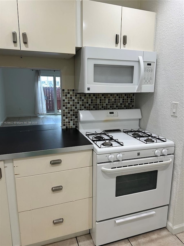 kitchen featuring white appliances, backsplash, and white cabinets