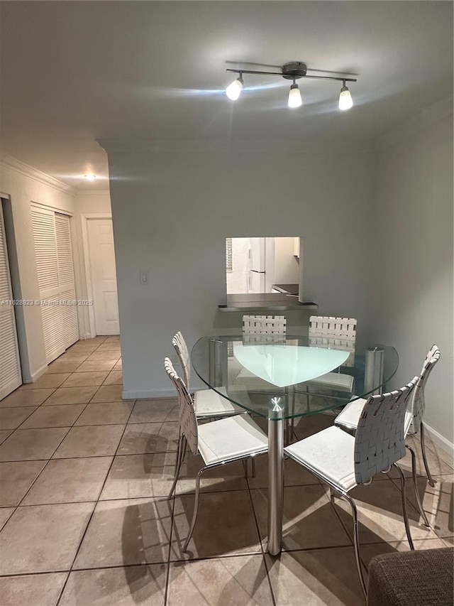 dining room with light tile patterned floors, track lighting, and crown molding