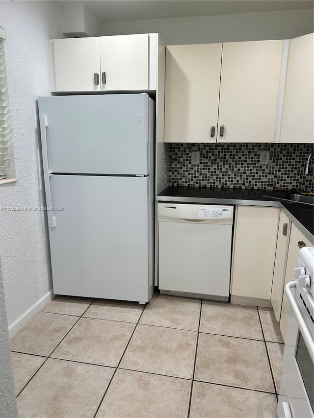 kitchen featuring white cabinetry, sink, backsplash, light tile patterned floors, and white appliances