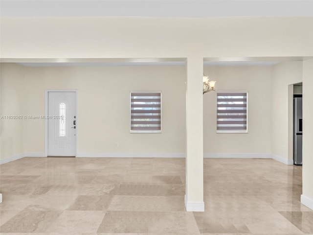 interior space featuring stainless steel fridge, a wealth of natural light, and a notable chandelier