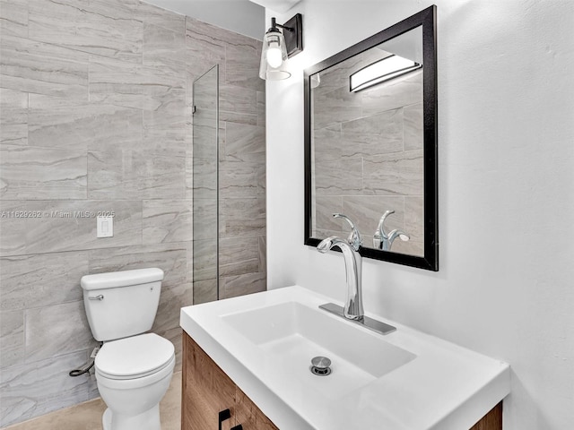 bathroom featuring toilet, vanity, and tile walls