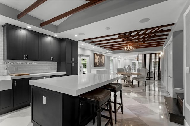 kitchen with a kitchen island, a kitchen breakfast bar, a notable chandelier, beam ceiling, and hanging light fixtures