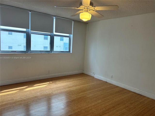 spare room featuring a textured ceiling, baseboards, a ceiling fan, and wood finished floors