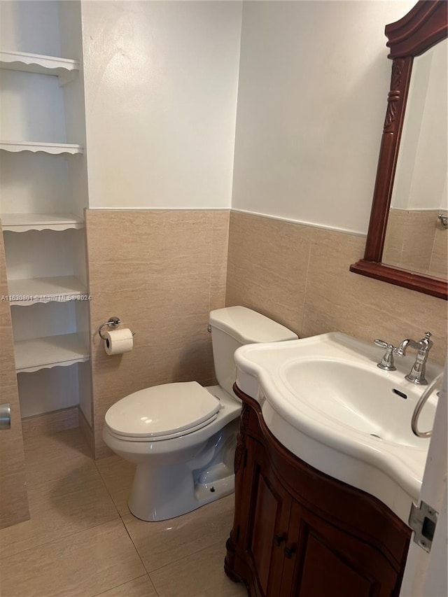 half bathroom featuring tile patterned floors, toilet, wainscoting, and vanity