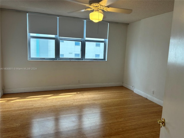 empty room with a textured ceiling, baseboards, a ceiling fan, and wood finished floors