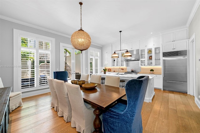 dining space featuring ornamental molding, sink, and light hardwood / wood-style flooring