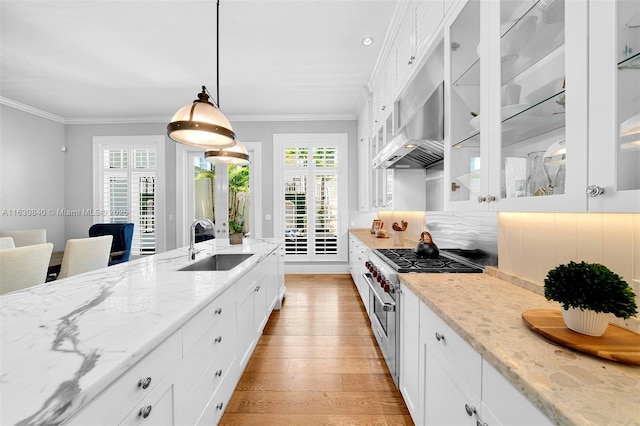 kitchen featuring white cabinetry, sink, high end range, and hanging light fixtures