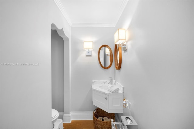 bathroom with wood-type flooring, vanity, toilet, and ornamental molding